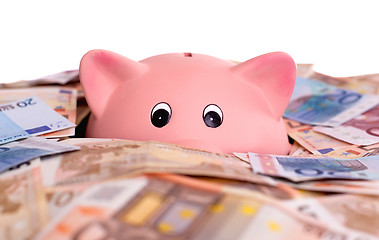 Image showing Unique pink ceramic piggy bank drowning in money