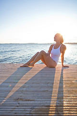 Image showing Attractive woman sitting on pier