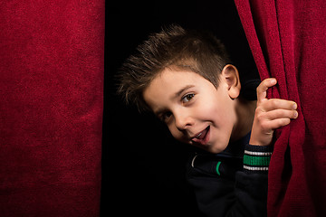 Image showing Child appearing beneath the curtain