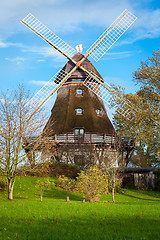 Image showing Traditional wooden windmill in a lush garden