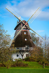 Image showing Traditional wooden windmill in a lush garden