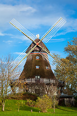 Image showing Traditional wooden windmill in a lush garden