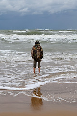 Image showing The teenager costs on the seashore in rainy weather a back in a 
