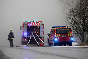 Image showing Fireman Emerging from Smoke with Fire Trucks on the Street