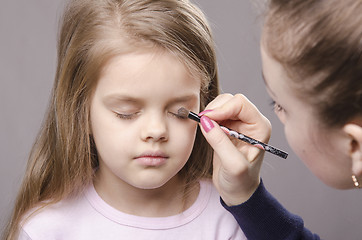 Image showing Makeup artist paints eyelids on girl's face