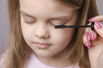 Image showing Makeup artist paints eyelashes on girl's face