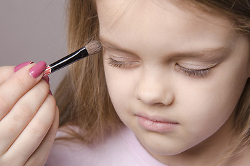 Image showing Makeup artist paints eyelids on girl's face