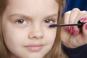 Image showing Makeup artist paints eyelashes on girl's face