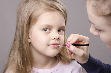 Image showing Makeup artist paints her lips girls