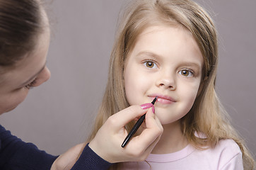 Image showing Makeup artist paints her lips girls