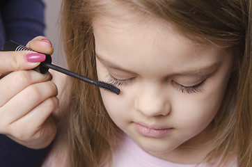 Image showing Makeup artist paints eyelashes on girl's face