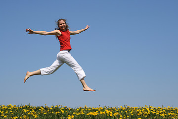 Image showing Girl flying in a jump over dandelion field