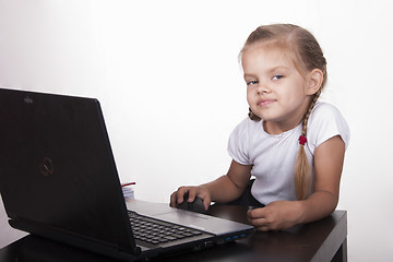 Image showing girl sitting at table and quietly working behind notebook