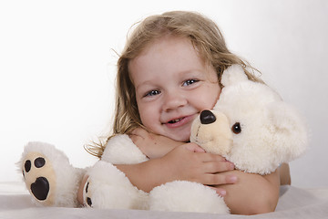 Image showing Two-year-old girl lies and bear hugs