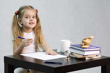 Image showing girl happily looks in frame, sitting at table image of writer