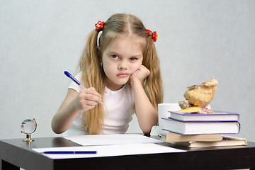 Image showing girl writes on a piece of paper sitting at table in image writer