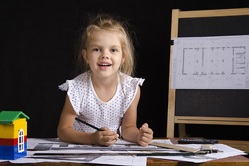 Image showing Girl-architect sitting behind Desk and looks in frame
