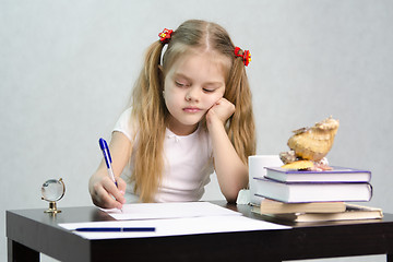 Image showing girl writes on a piece of paper sitting at table in image writer