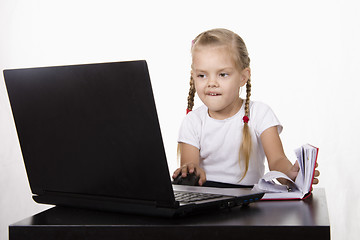 Image showing girl working at laptop, and records in notebook