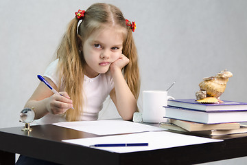 Image showing girl writes on a piece of paper sitting at table in image writer
