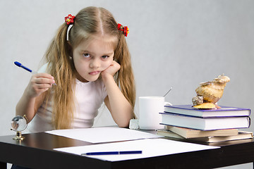 Image showing girl writes on a piece of paper sitting at table in image writer