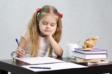 Image showing girl writes on a piece of paper sitting at table in image writer