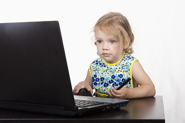 Image showing girl working at a laptop and looked mysteriously in frame