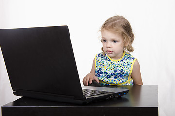 Image showing girl working at a laptop and looked mysteriously in frame