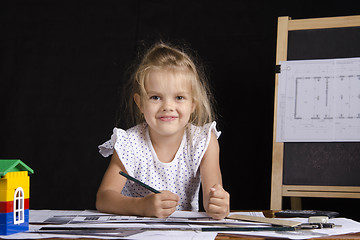 Image showing Girl-architect sitting behind Desk and looks in frame