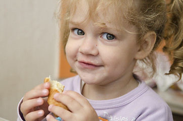 Image showing little girl with enthusiasm and eats roll pleasure