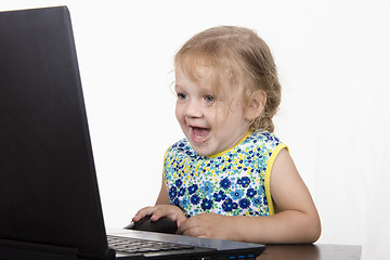 Image showing girl working at a laptop and looked mysteriously in frame