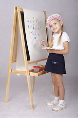 Image showing The girl in image of artist draws on easel