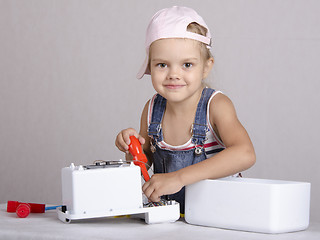 Image showing Girl repairs screwdriver toy microwave