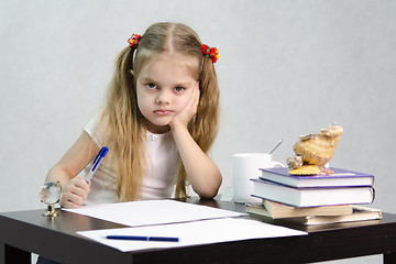 Image showing girl writes on a piece of paper sitting at table in image writer