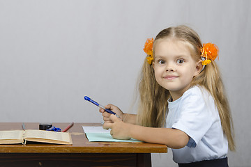 Image showing Little girl sitting at table and wrote in notebook