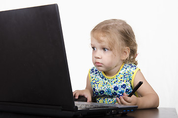 Image showing girl working at a laptop and looked mysteriously in frame