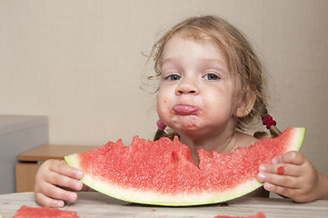 Image showing Two-year-old girl eating watermelon with cheerful faces