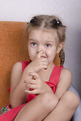 Image showing Girl sitting on the couch and picks his nose