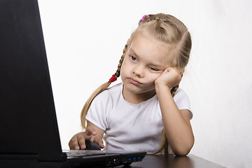 Image showing girl sitting at table and quietly working behind notebook