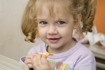 Image showing little girl with enthusiasm and eats roll pleasure