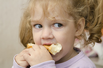 Image showing little girl with enthusiasm and eats roll pleasure