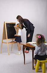 Image showing At blackboard girl with tutor draw shapes, another sitting table