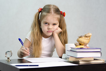 Image showing girl writes on a piece of paper sitting at table in image writer