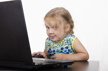 Image showing girl working at a laptop and looked mysteriously in frame