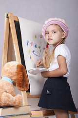 Image showing The girl in image of artist draws on easel