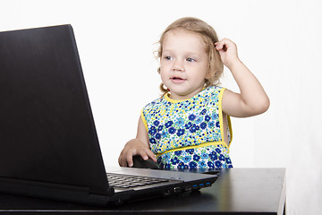 Image showing girl working at a laptop and looked mysteriously in frame