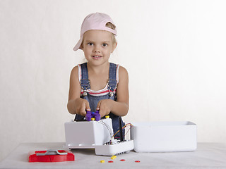 Image showing Girl twists nut pliers, repairing toy