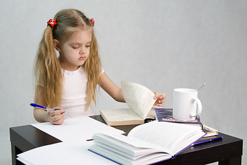 Image showing Girl leafing through book and wrote on a sheet of paper abstract sitting