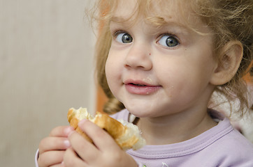 Image showing little girl with enthusiasm and eats roll pleasure