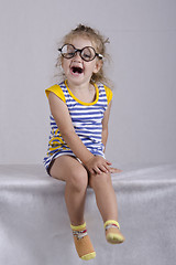 Image showing Two-year-old girl in funny glasses sits and laughs cheerfully